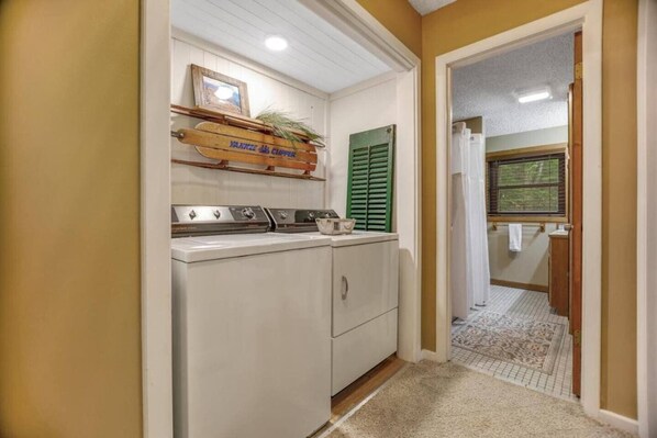 A laundry area with a washing machine, a drying rack, and a wooden sign above the machine. - Rushing Creek Retreat, Serene Cabin with Great Views! (Sylva)