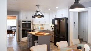A modern kitchen with white cabinets, a central island, stainless steel appliances, and a pendant light. - Loveta Hideaway (Mount Shasta)