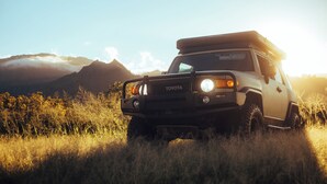Een Toyota SUV geparkeerd in een grasveld, met bergen op de achtergrond.