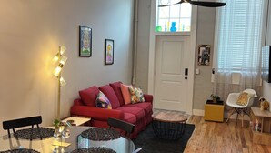 Un salon moderne avec une table à manger en verre, un canapé rouge et un ventilateur de plafond.