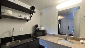 Una cocina moderna con encimera de granito, pileta de acero inoxidable y cafetera.