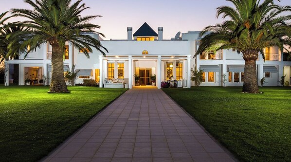 Stunning two-story building with a central entrance and palm trees, set amidst a modern architectural style.