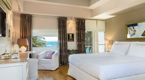 Relax in this serene space with a large bed, a cozy seating area, and a view of the outdoors.