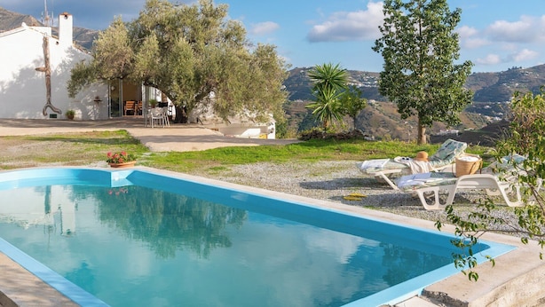 A rectangular swimming pool with a clear blue water surface, surrounded by a gravel area with lounge chairs and a small garden. - Reiner Canillas de Albaida by Ruralidays (Málaga)