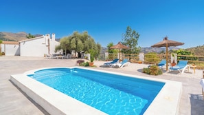 A swimming pool with lounge chairs and a pergola with a thatched roof. - Reiner Canillas de Albaida by Ruralidays (Málaga)