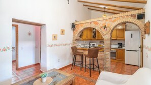 A compact living space with a kitchen, a dining area with two stools, and a white sofa. - Reiner Canillas de Albaida by Ruralidays (Málaga)