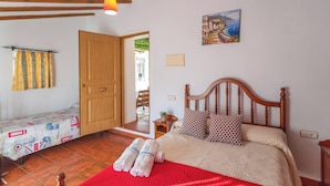 A bedroom with a wooden bed, a red blanket, and a small bedside table. - Reiner Canillas de Albaida by Ruralidays (Málaga)