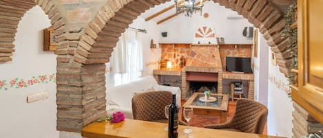 A dining area with a brick archway, a fireplace, and a television in the background.