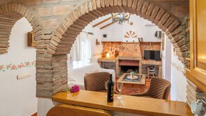 Un coin repas agrémenté d’une arche en briques, d’une cheminée et d’un téléviseur placé à l’arrière-plan.