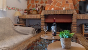 A cozy living room with a stone fireplace, a sofa, a coffee table, and a television. - Reiner Canillas de Albaida by Ruralidays (Málaga)