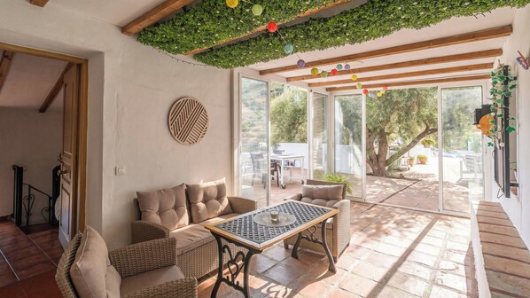 Un espace patio intérieur aménagé avec des meubles en osier, une table et une vue sur l’extérieur.