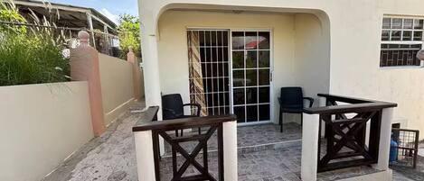 Un'area patio con due tavoli e sedie, una porta scorrevole in vetro e un piccolo angolo salotto all'aperto.