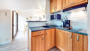A compact kitchen with wooden cabinets, a microwave, a coffee maker, and a sink.