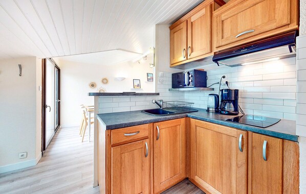 A compact kitchen with wooden cabinets, a microwave, a coffee maker, and a sink.