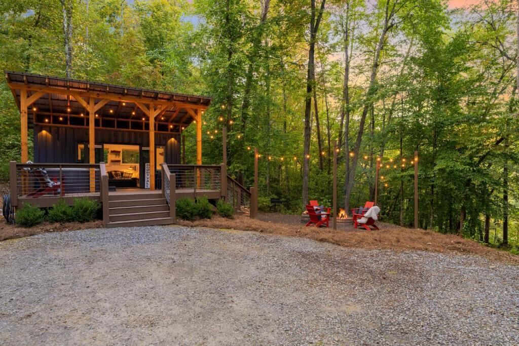 A rustic cabin with a wooden exterior, a covered porch, and a gravel driveway.