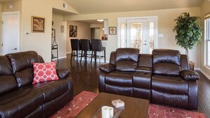 Ein Wohnzimmer mit Ledersofas, einem Couchtisch und einem Essbereich mit Stühlen.