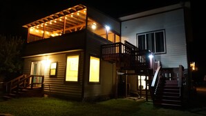 A two-story house with a covered deck and a staircase leading to the upper level. - 2nd-Story Covered Deck with Lake View - 2 Kings, 3 Queens! (Canyon Lake)