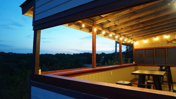 A covered outdoor area with a wooden deck, a table, and chairs. - 2nd-Story Covered Deck with Lake View - 2 Kings, 3 Queens! (Canyon Lake)