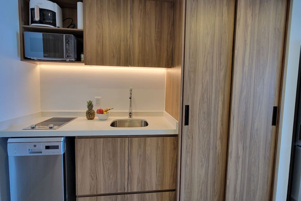 Une cuisine compacte dotée de meubles en bois, d’un four à micro-ondes, d’un évier et d’un lave-vaisselle.
