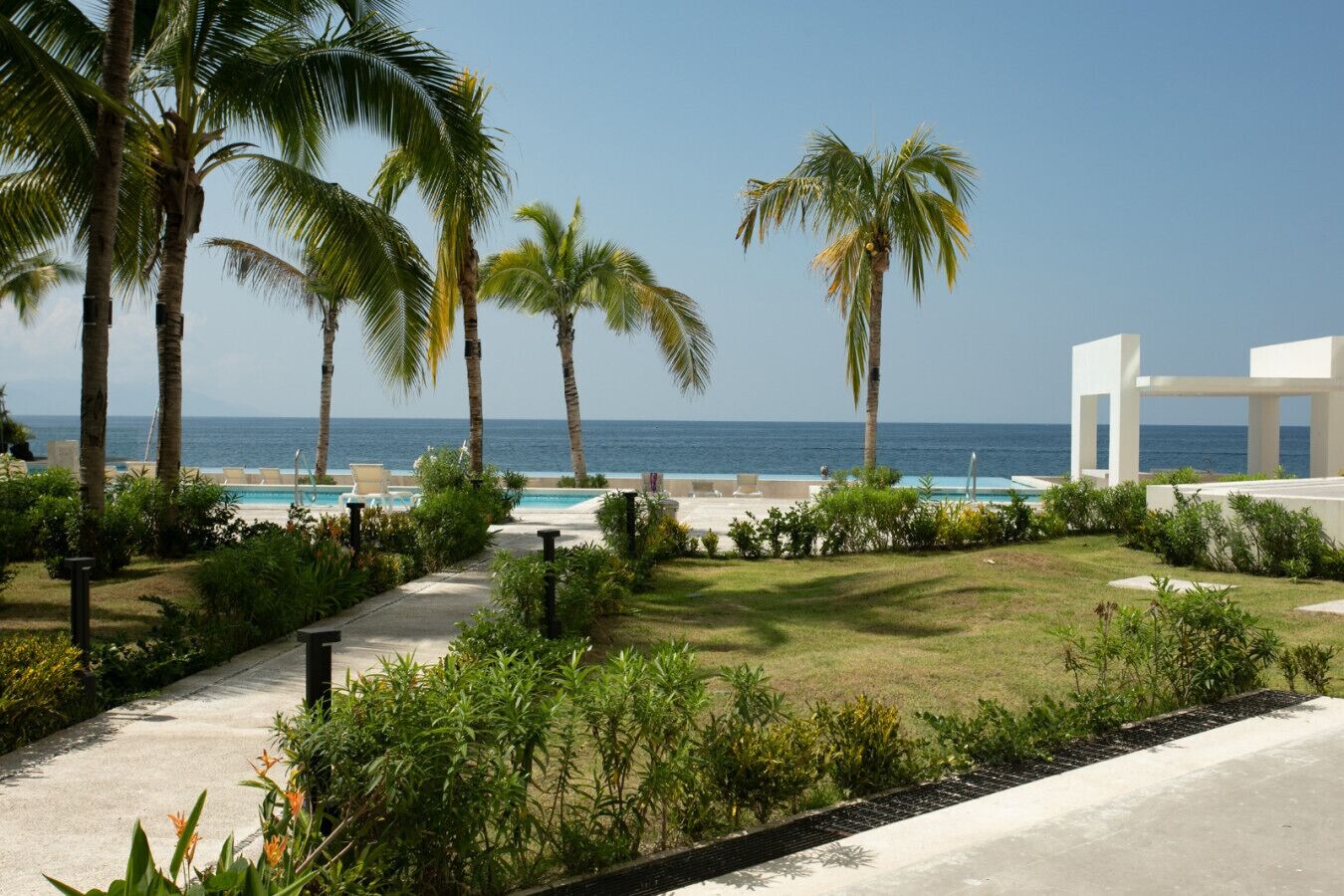 A resort with a pool, palm trees, and a view of the ocean.