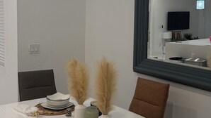 A modern dining area with a white table set for four, including plates, bowls, and decorative items. - Belle Ville  (Lehigh Acres)