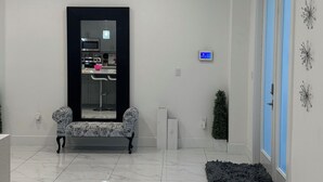 A modern, well-lit hallway with a marble floor, a bench, a small plant, and a decorative wall piece. - Belle Ville  (Lehigh Acres)