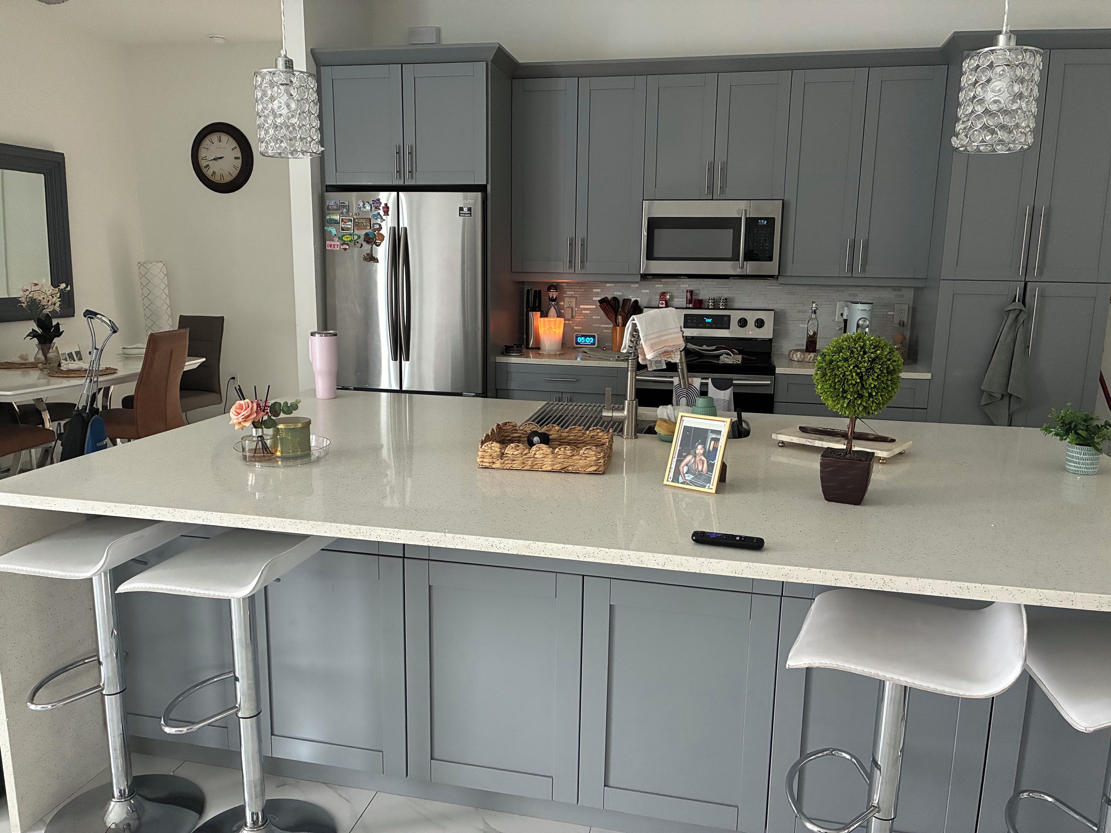 A modern kitchen with grey cabinets, stainless steel appliances, and a central island with bar stools.