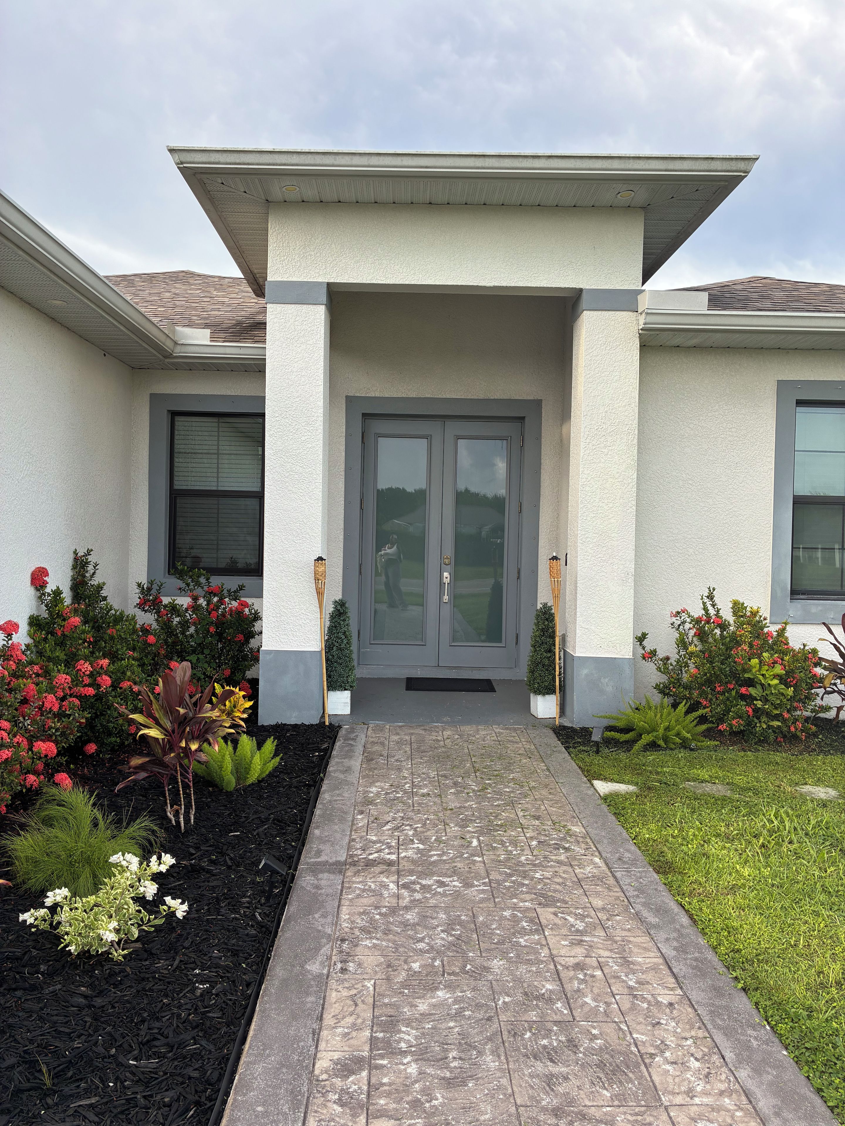 A house with a front entrance, two windows on either side, and a pathway leading to the door.