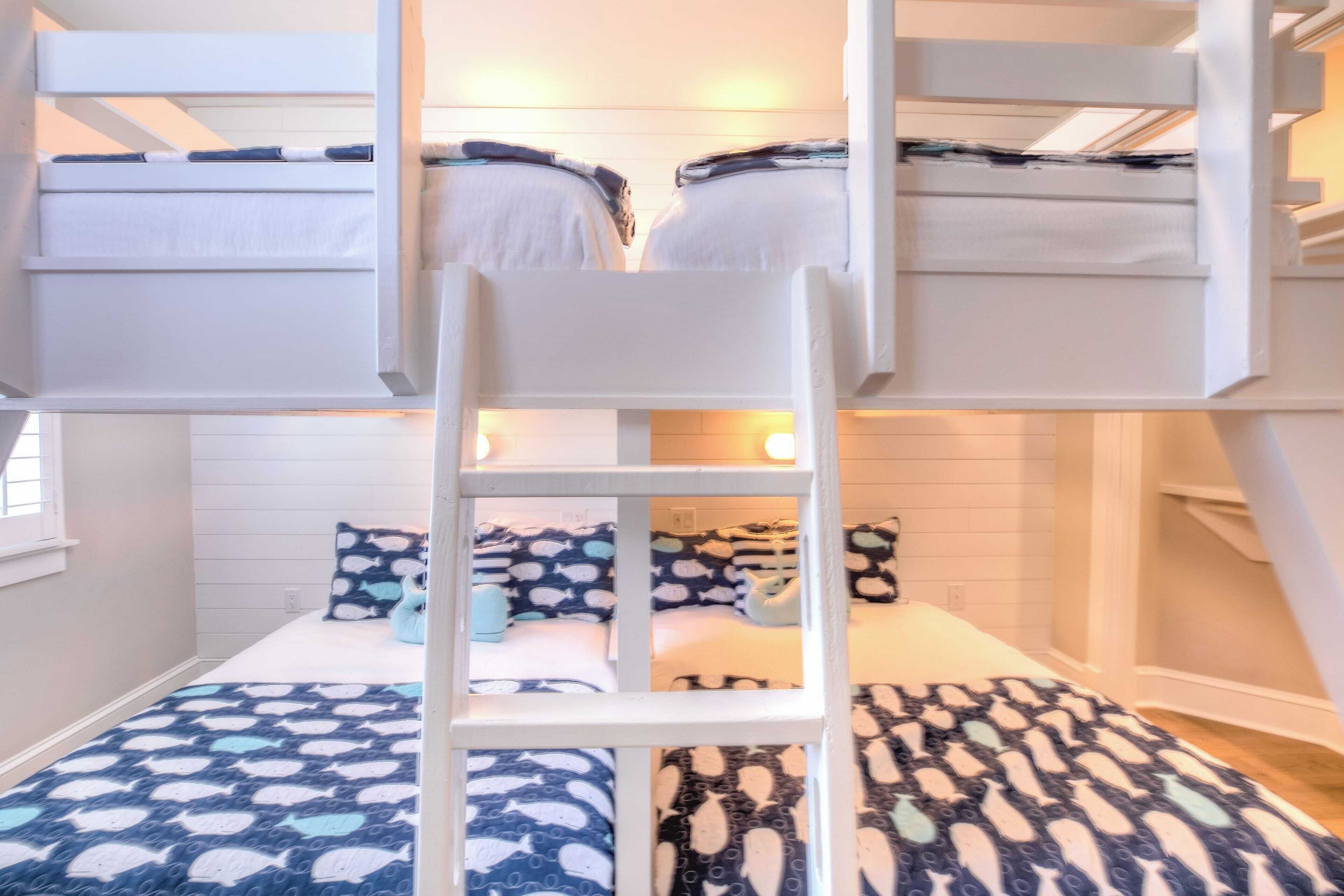 Ein Schlafzimmer mit Etagenbetten, einer Leiter, zwei Betten und einem Fenster.