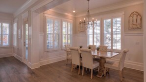 A dining room with a large wooden table, six chairs, and a chandelier.