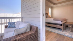 A balcony with a wicker sofa and a bed with a wooden headboard.