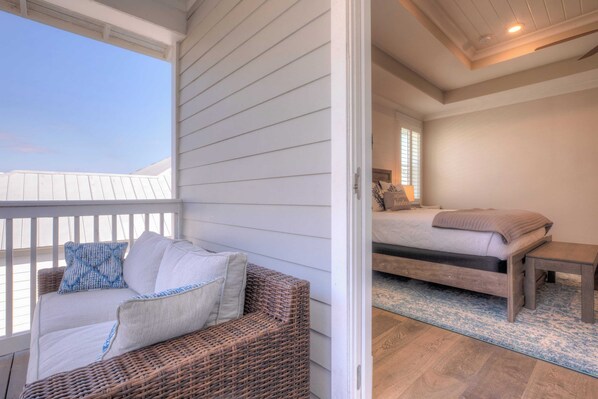 Un balcon avec un canapé en osier et un lit doté d’une tête de lit en bois.
