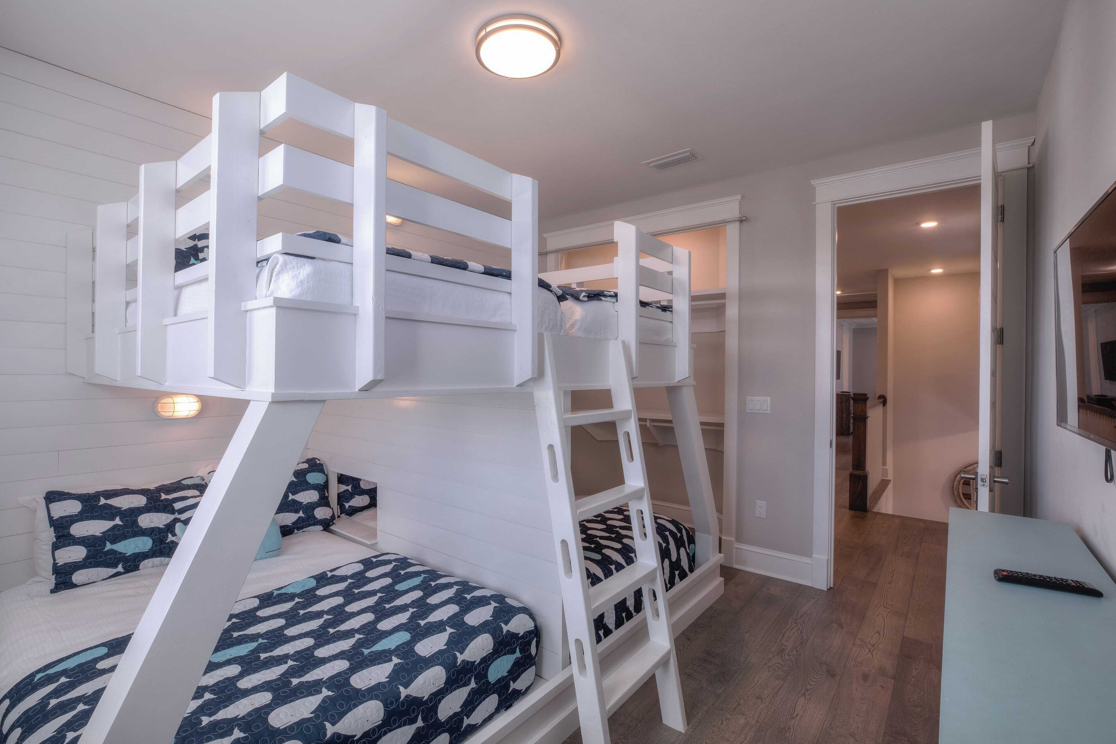 A bunk bed room with a desk and a TV.