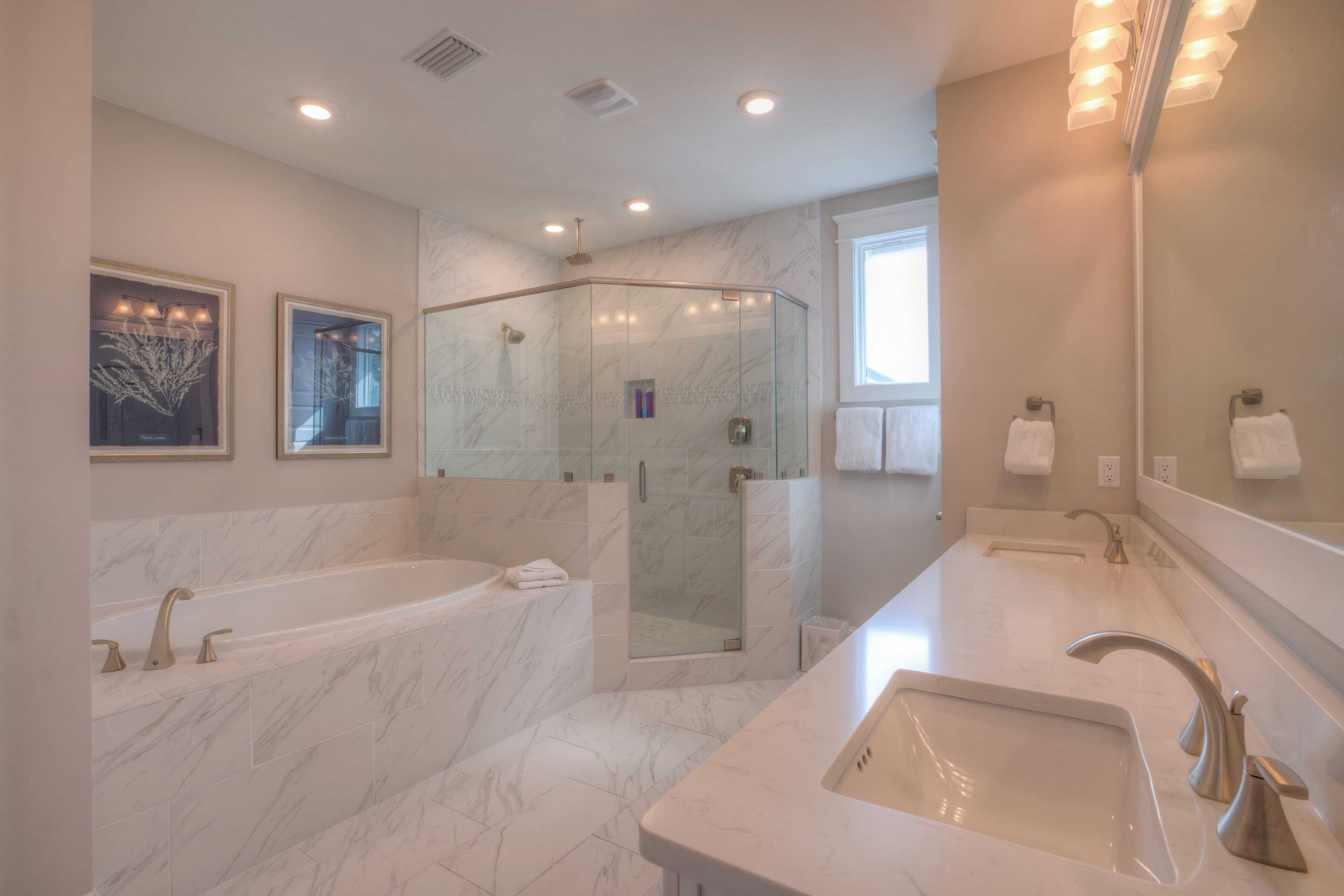 Un bagno moderno con una grande vasca da bagno, una doccia a filo pavimento e un lavabo con specchio.