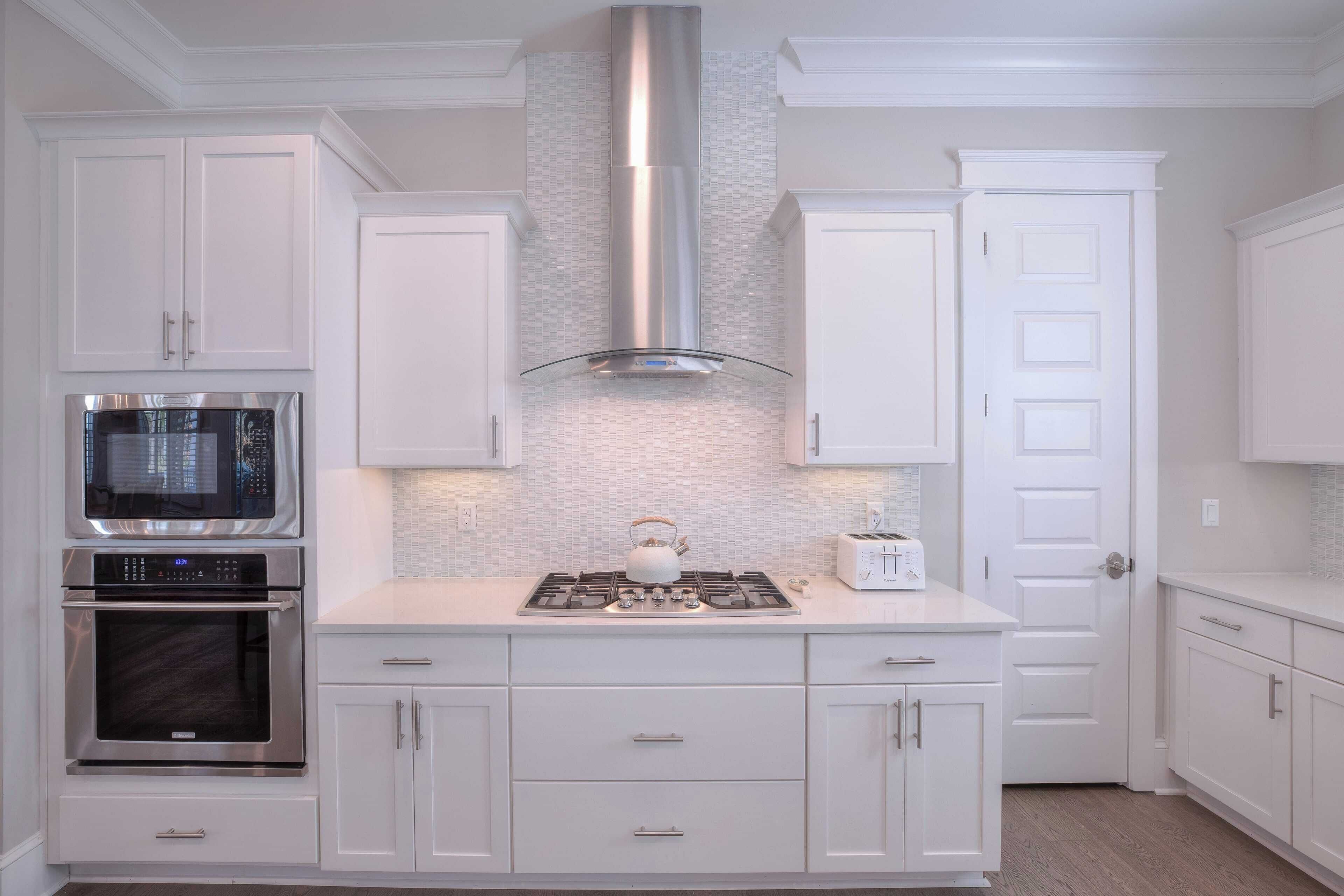 A modern kitchen with white cabinetry, stainless steel appliances, and a tiled backsplash.