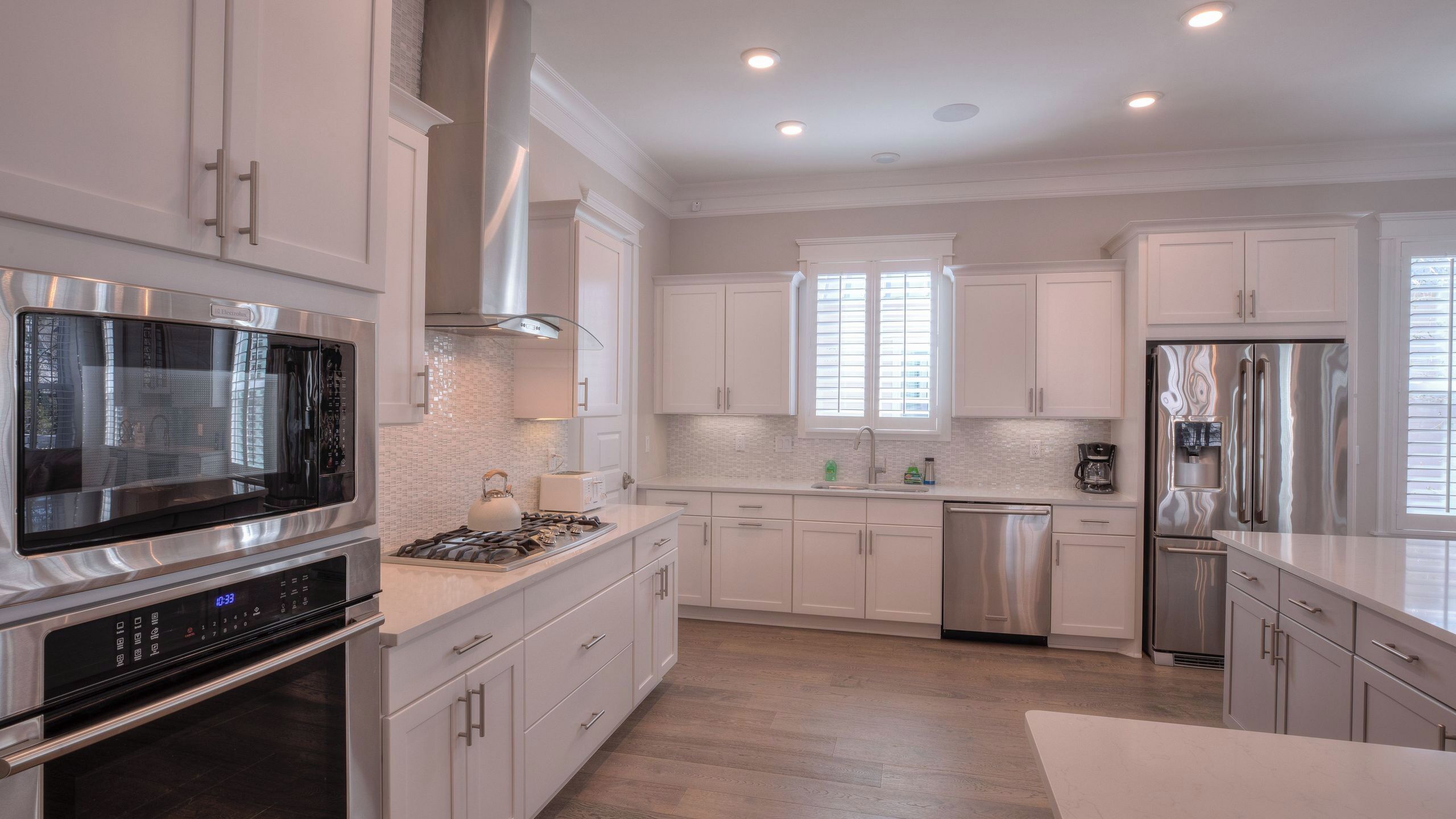 A modern kitchen with stainless steel appliances, white cabinetry, and a large window.