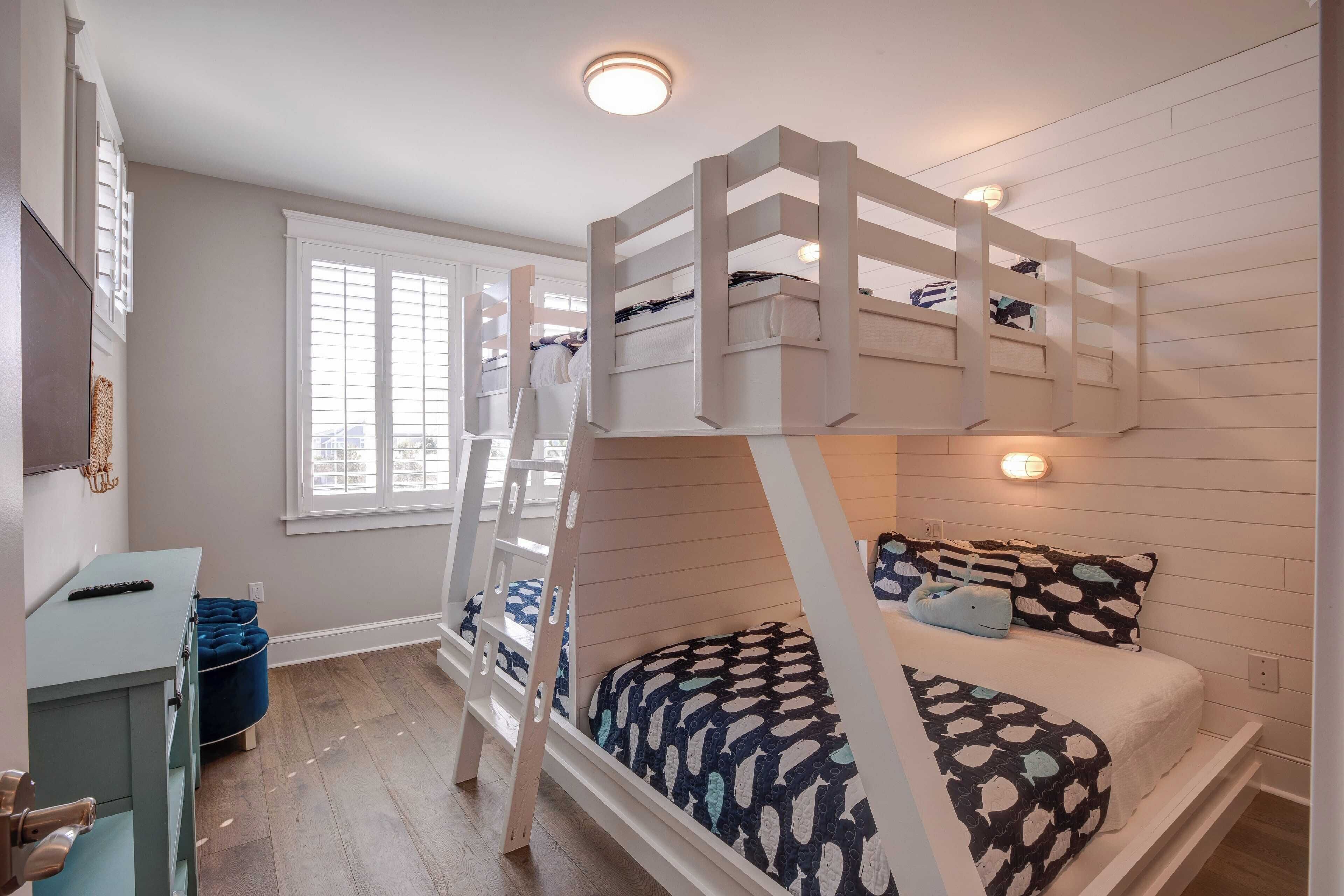 A bunk bed with a ladder, a desk with a chair, and a window with blinds.