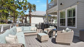 Een terras buiten met een bank, stoelen en een barbecue.