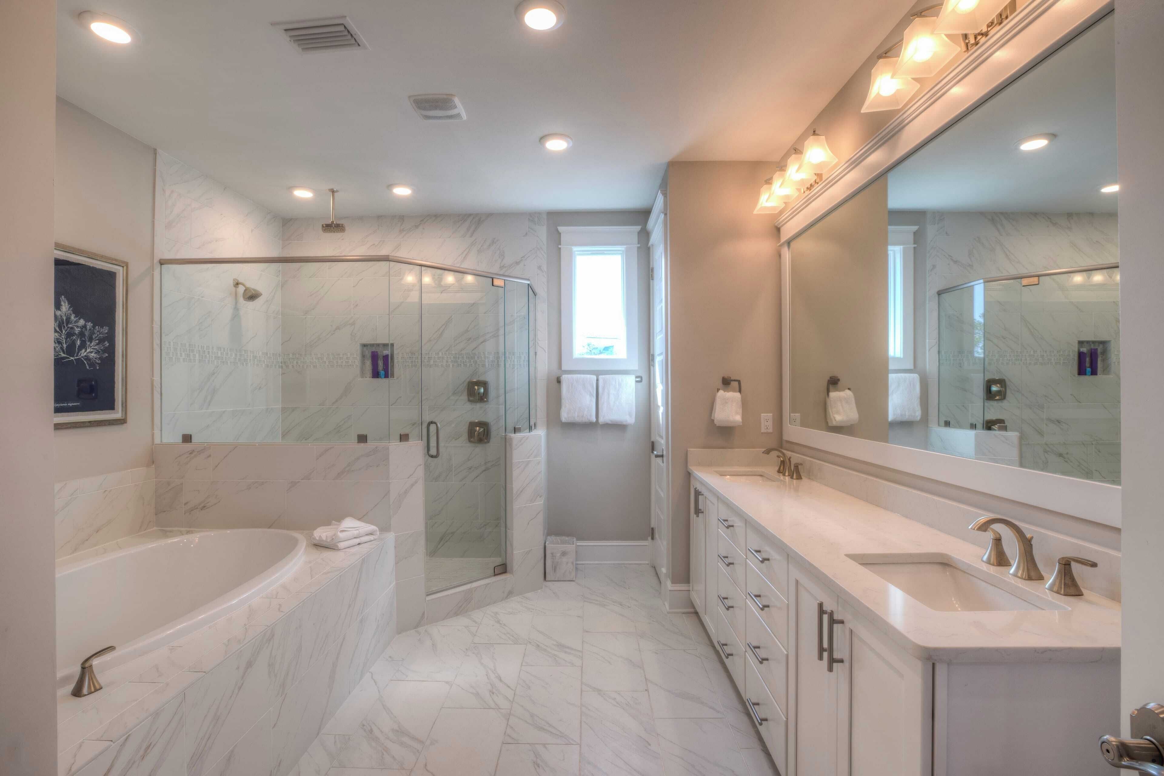 A modern bathroom with a large bathtub, a walk-in shower, and a vanity with a mirror.