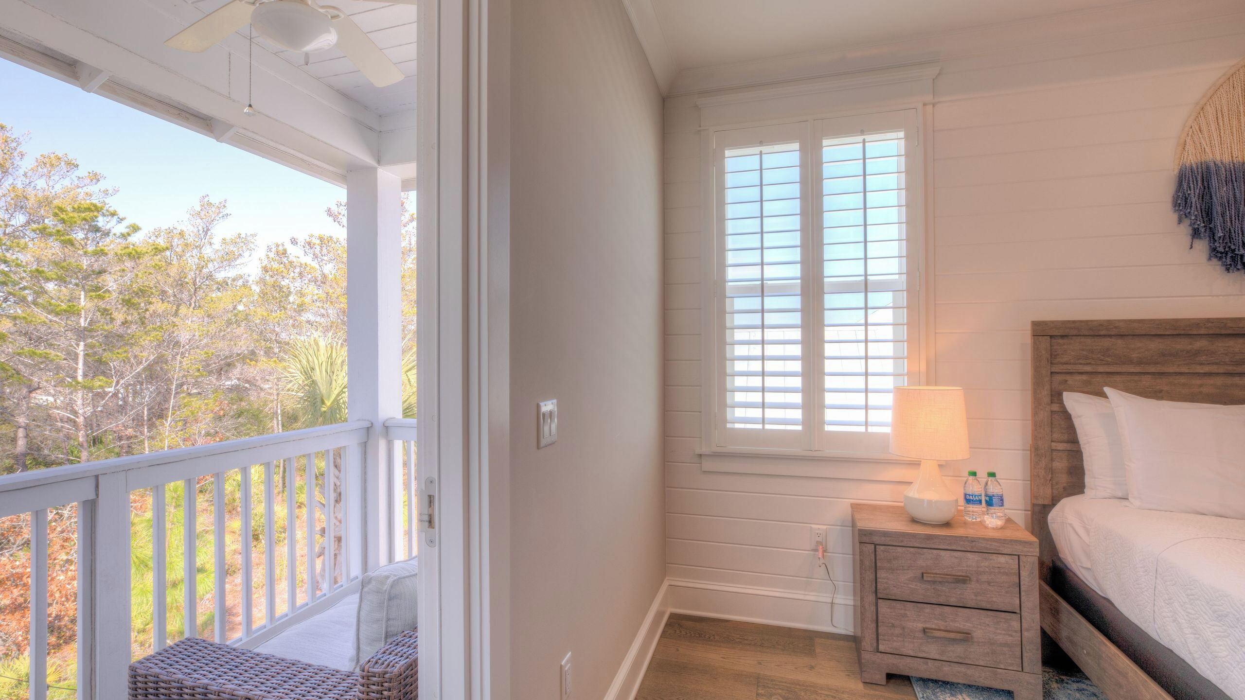 A bedroom with a bed, nightstand, lamp, and window with blinds.