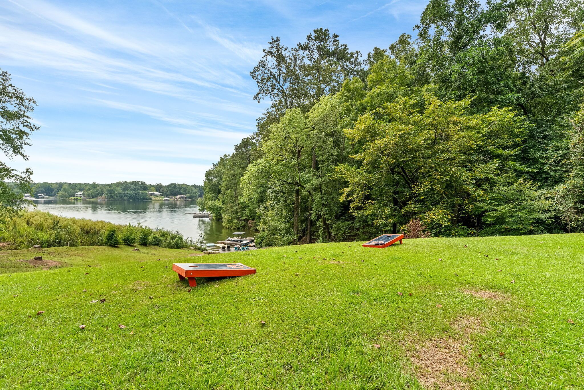 Une zone herbeuse avec un lac et des bateaux, entourée d’arbres.