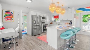 A modern kitchen with white cabinetry, stainless steel appliances, and a central island with bar stools. - Chic Getaway Near Wilton Drive l Heated Pool (Wilton Manors)