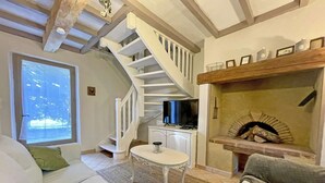 A living room with a white staircase, a fireplace, and a television on a cabinet.
