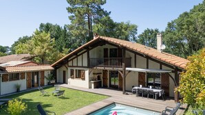 Una casa a due piani con patio, piscina e zona pranzo.