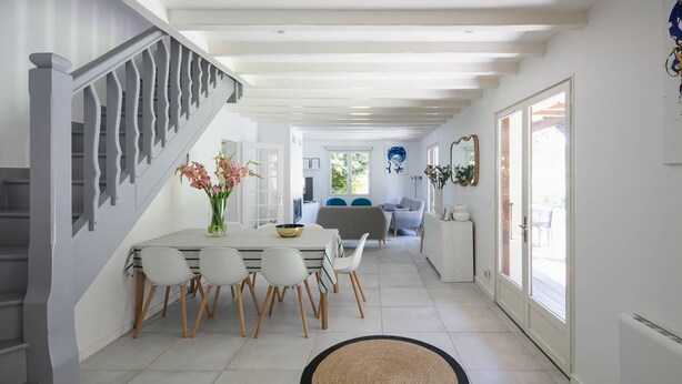 Una cucina moderna con zona pranzo, che include una scala, un tavolo da pranzo con sedie e un'ampia finestra che fa entrare luce naturale.