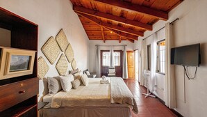 A bedroom with a bed, a TV, a wooden ceiling, and a door. - House in an exclusive safe and nice condo (Antigua Guatemala)