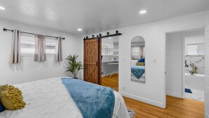 A bedroom with a bed, a sliding door, a mirror, and a view into a bathroom.