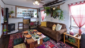 A cozy living room with a fireplace, a ceiling fan, and a dining area with a table set for a meal.