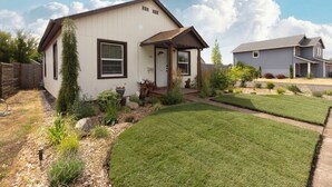 A single-story house with a front porch, a well-maintained lawn, and a small garden area with various plants and flowers.