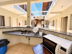 A kitchen with a central island, a microwave, and a sink. - Hotel Picadão Eventos (São Pedro)